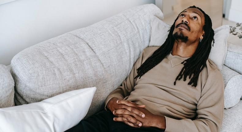 Pensive black man lying on couch [Photo: Alex Green]