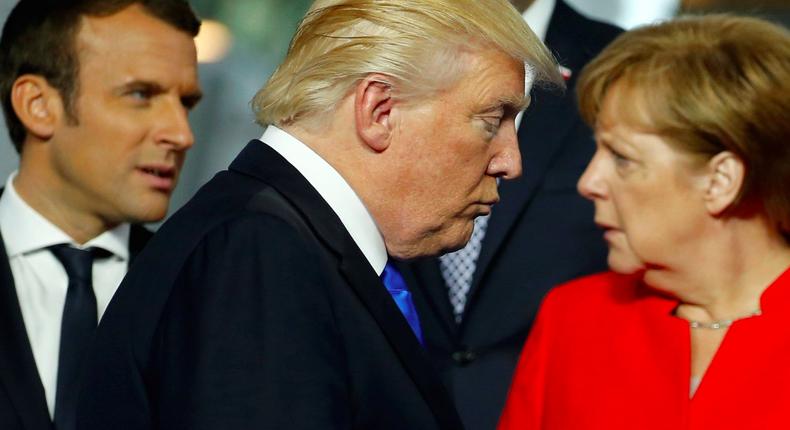 U.S. President Donald Trump (C) walks past French President Emmanuel Macron (L) and German Chancellor Angela Merkel on his way to his spot for a family photo during the NATO summit at their new headquarters in Brussels, Belgium May 25, 2017.