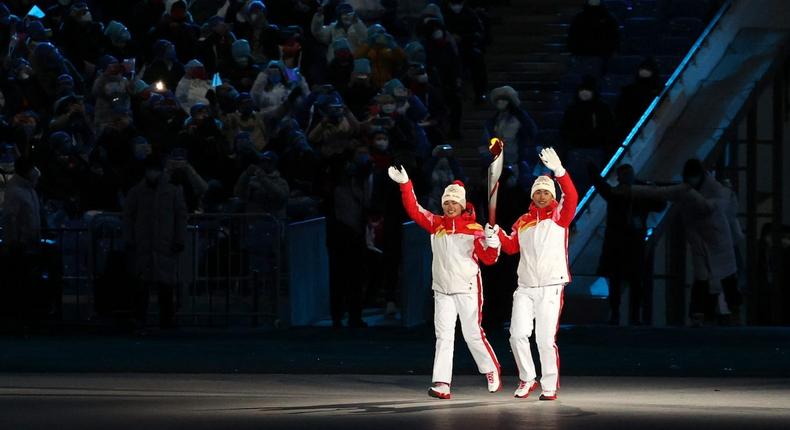 Chinese athletes Dinigeer Yilamujiang and Zhao Jiawen carry the Olympic torch at the opening ceremony of the Beijing 2022 Winter Olympic Games at the National Stadium.