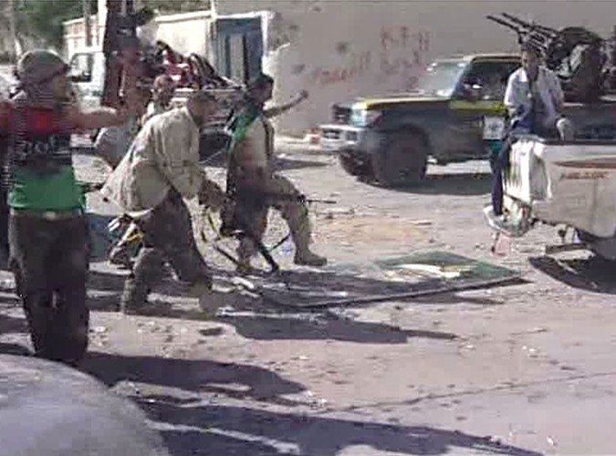 Powstańcy libijscy niszczą portret Kadafiego na ulicach Syrty