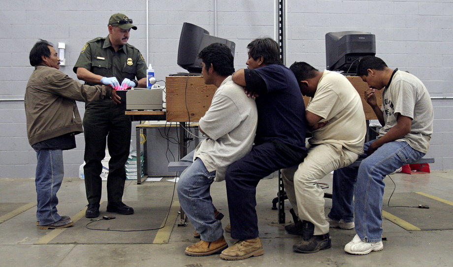 A man has his fingerprints electronically scanned by a US Border Patrol agent while others wait for their turn at the US Border Patrol detention center in Nogales, Arizona, May 31, 2006.
