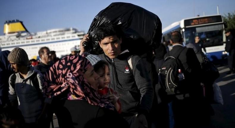 An Afghan refugee carries his belongings as he and his family wait to board a bus, following the arrival of refugees and migrants by the Blue Star Patmos passenger ferry from the island of Lesbos at the port of Piraeus, near Athens, Greece, October 14, 2015. REUTERS/Alkis Konstantinidis