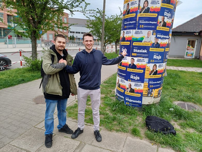 Mateusz (od lewej) i Emil na tle słupa oblepionego plakatami kandydatów na radnych z komitetu Patryka Marjana