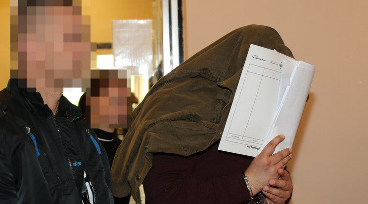 A vádlott arcát kabátjával és papírjaival eltakarva érkezett meg a tárgyalásra /Fotó: Grnák László