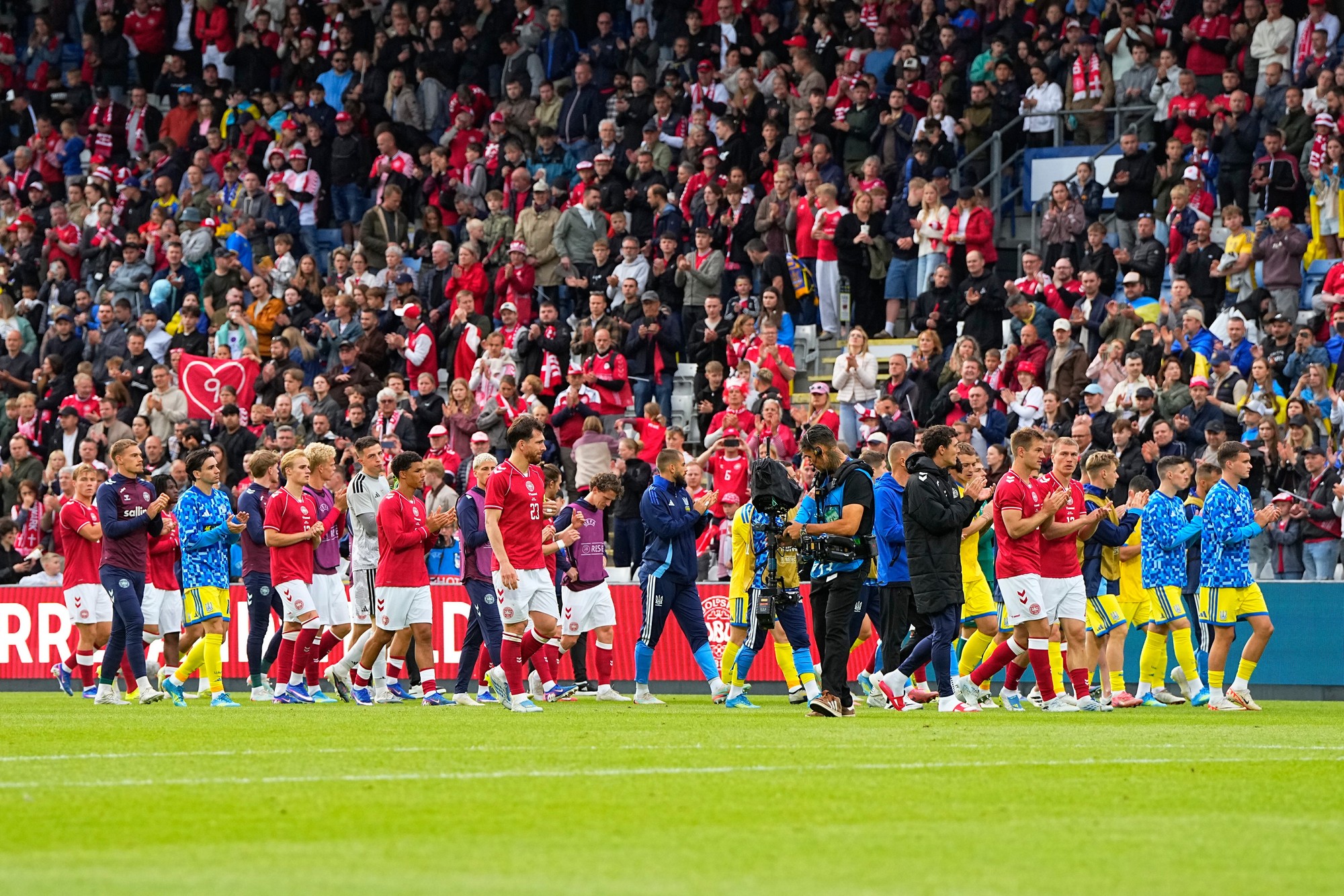 Hráči Dánska a Ukrajiny kráčajú po ihrisku po zrušení medzinárodného priateľského futbalového zápasu po tom, čo Christian Eriksen opäť skolaboval na ihrisku.