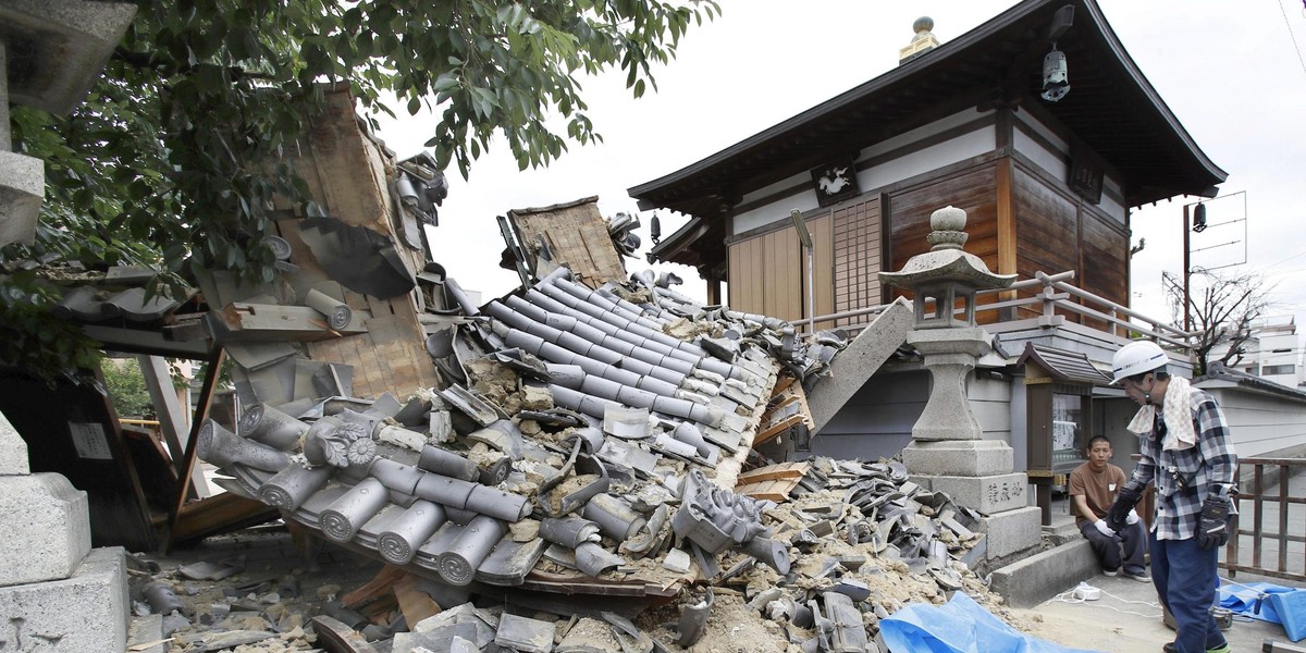 Employees try to remove bottles and cans of beverages which are scattered by an earthquake at a liquor shop in Hirakata