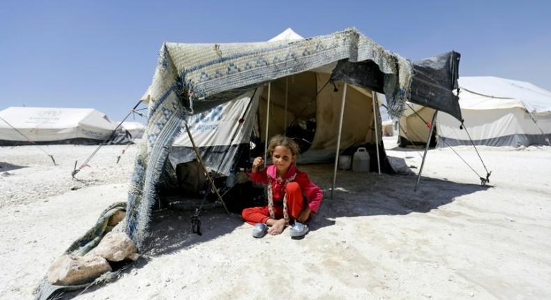 A Syrian girl, who fled the countryside surrounding the Islamic State group's Syrian stronghold of Raqa, sits in the shade of a tent at a temporary camp in the village of Ain Issa on July 11, 2017