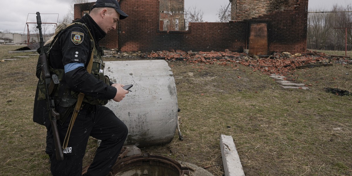 Ukraiński policjant fotografuje martwe ciało 44-letniego Hennadija Mierczynskiego, zabitego przez wojska rosyjskie i wrzuconego do studni, we wsi Motyżyn na Ukrainie.