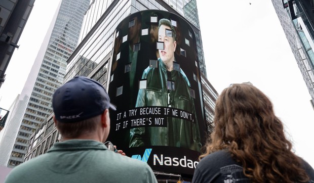 Posmatrači gledaju kako se na ekranu na Tajms skveru pojavljuje Ilon Mask, osnivač kompanije SpaceX, tokom inicijalne javne ponude akcija (IPO) kompanije u Nasdaq MarketSite centru, 12. juna 2026. godine u Njujorku.