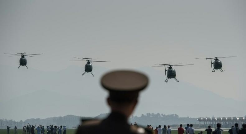 A North Korean soldier watches as Hughes MD-500 helicopters perform a fly-by during the first Wonsan Air Show in September 2016