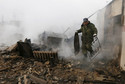 Local resident Sergei Shvedchikov carries scrap metal from his burnt house in the settlement of Shyra, damaged by recent wildfires, in Khakassia region