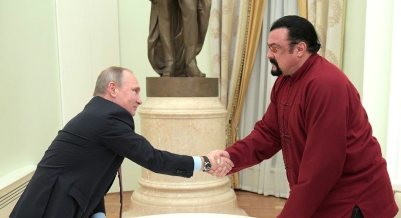 Vladimir Putin (left) shakes hands with Steven Seagal after presenting him with a Russian passport during a meeting at the Kremlin in Moscow, on November 25, 2016