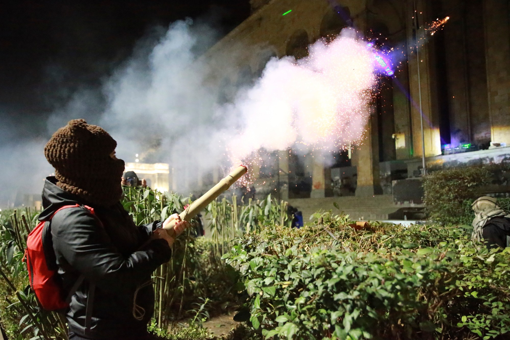 Demonštranti odpaľujú petardy do parlamentu počas protestu proti rozhodnutiu vlády pozastaviť rokovania o vstupe do Európskej únie v gruzínskom meste Tbilisi v piatok 6. decembra 2024.