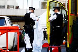 Police officers unfold a sheet infront of a body covered with a blanket after the London Ambulance Service reported that a man collapsed and died from a heart attack in the Mayfair district of central London