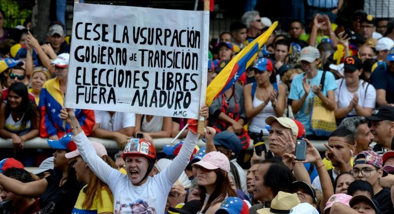 A woman holds a poster demanding free elections during an opposition rally against leader Nicolas Maduro