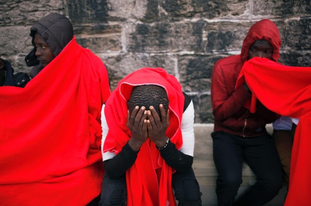 Migrants rest after arriving on a rescue boat at the port of Tarifa