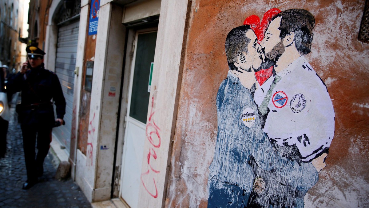 An Italian Carabiniere stands next to a mural depicting Northern League's leader Matteo Salvini and 