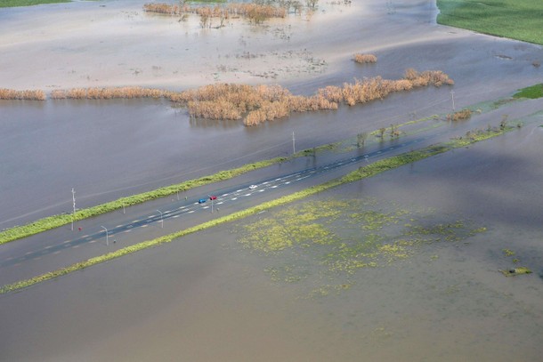 A supplied image shows three vehicles stranded on a highway flooded after Cyclone Debbie passed thro