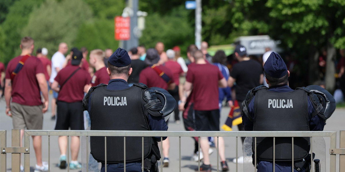 Funkcjonariusze policji nadzorują wejście na stadion przez kibiców Pogoni.
