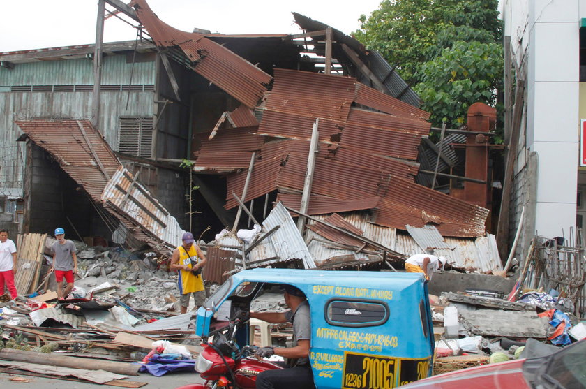 Workers clear concrete debris as they search for possible casualties at the ruins of an old building