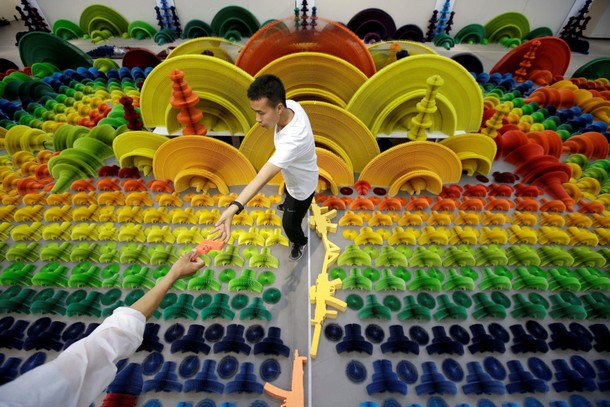 Chinese artist Li Hongbo gets a paper sculpture in the shape of a handgun from his assistant as he s