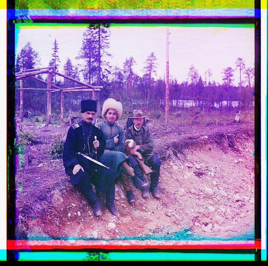 Photographer Sergeĭ Mikhaĭlovich Prokudin-Gorskiĭ and two men in Cossak dress seated on the ground.