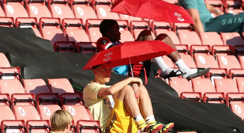 Arsenal's German midfielder Mesut Ozil (C) shelters from the sunshine