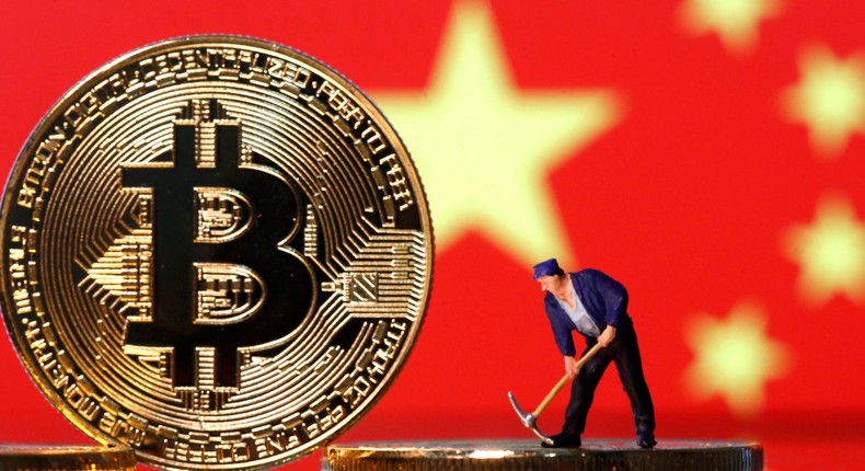 A small toy figurine is seen on representations of the bitcoin virtual currency displayed in front of an image of China's flag in this illustration picture, April 9, 2019.
