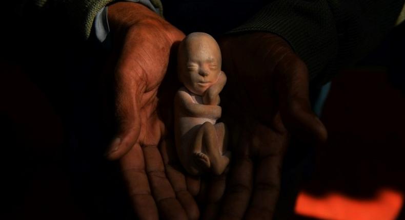 An Indian activist holds a model of a foetus during a protest against abortion in New Delhi