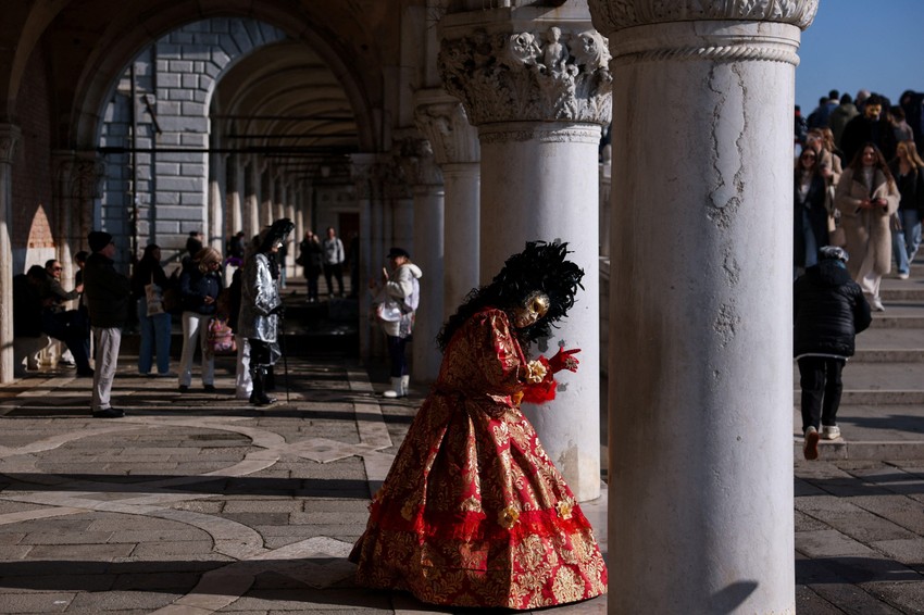 Učesnica karnevala u Veneciji stoji pored stuba na Trgu svetog Marka | Foto: REUTERS/Claudia Greco