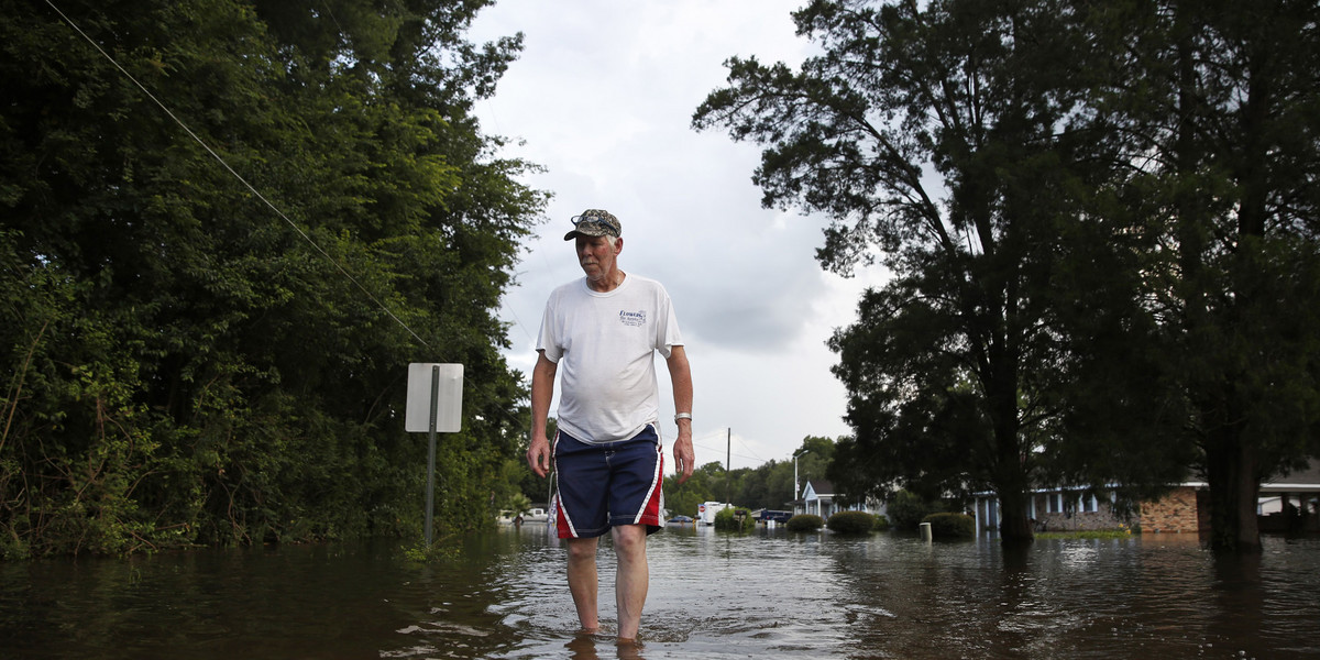 A man walks on the flooded street he lives on in Sorrento, Louisiana.