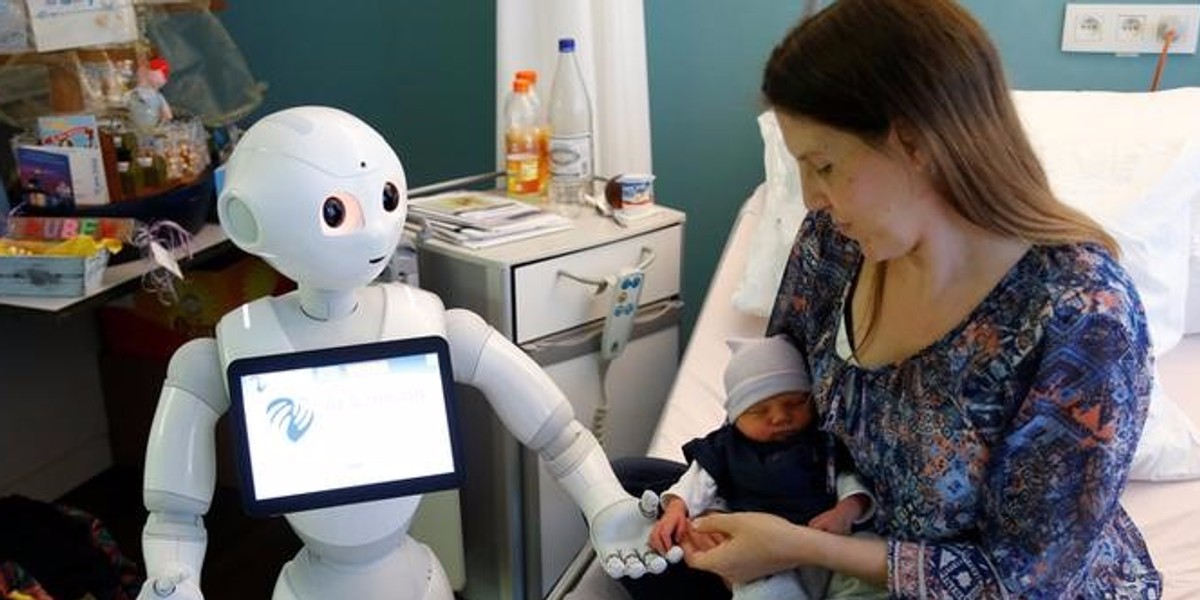 Pepper holding the hand of a newborn baby next to his mother at AZ Damiaan hospital in Ostend, Belgium.