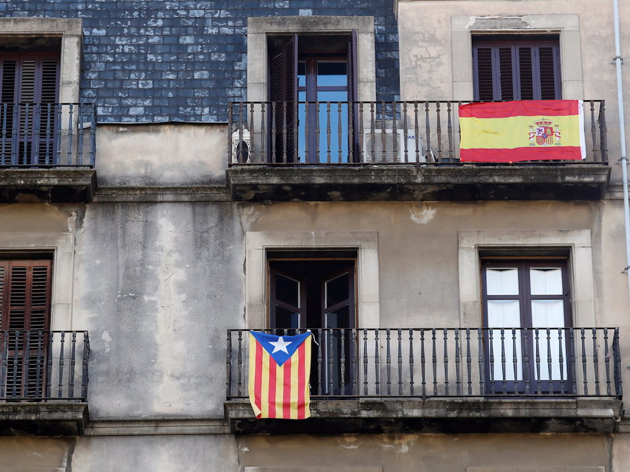 A Catalan separatist flag and the Spanish flag hanging from balconies in Barcelona.