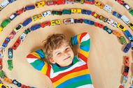 Cute little blond kid boy playing with lots toy cars