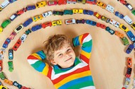 Cute little blond kid boy playing with lots toy cars