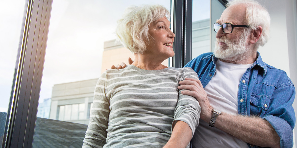 Happy old couple looking at each other at window