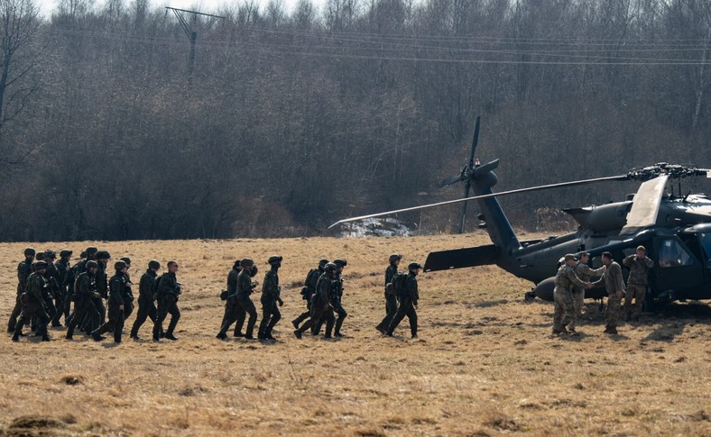 Żołnierze polscy (w ciemnych mundurach po lewej) i amerykańscy z 82. Dywizji Powietrznodesantowej ćwiczą załadunek helikopterów UH-60 Black Hawk w Birczy niedaleko Przemyśla, 15 marca 2022 r. 