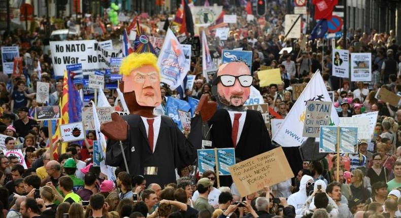 People carry effigies of US President Donald Trump (L) and Belgian Prime Minister Charles Michel during a demonstration against the US president in Brussels