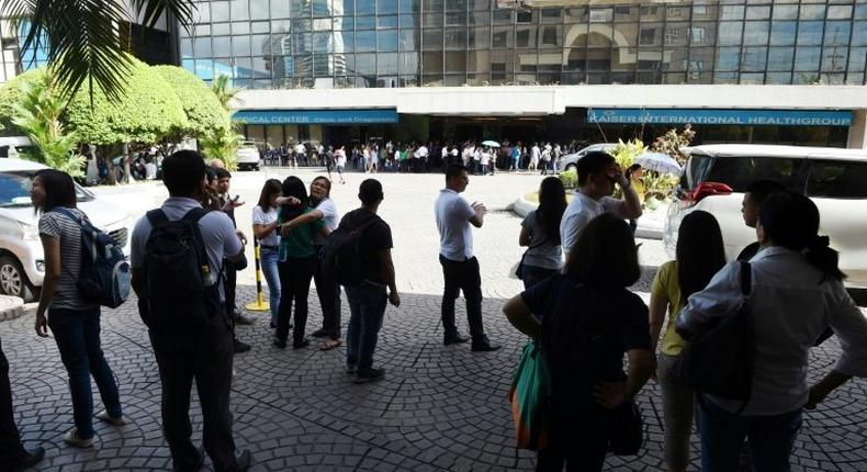 Office workers stand on the grounds of an office building in the financial district of Makati in Manila on April 8, 2017, after a 5.7 magnitude earthquake struck