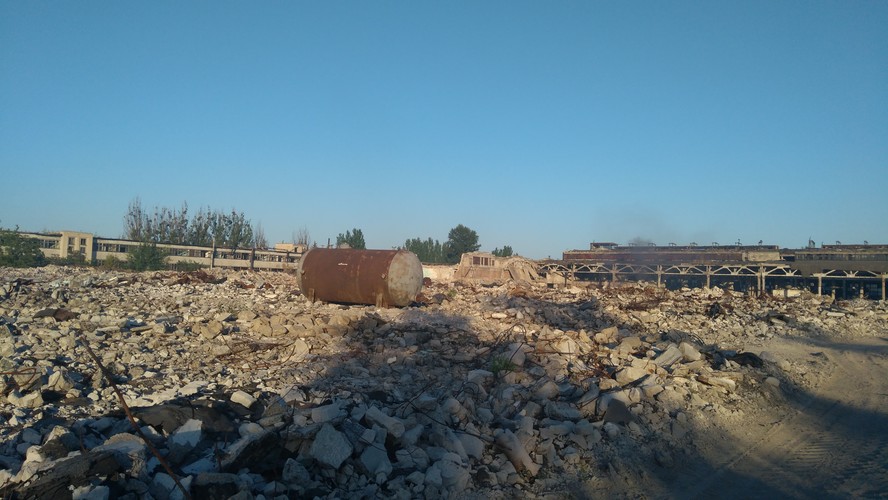 <br></br>
W 2014 roku Lisiczańsk przez trzy miesiące był pod okupacją kontrolowanych przez Rosję separatystów. W czasie wojny uszkodzono kilkaset budynków, a kilkudziesięciu mieszkańców miasta zginęło. Ale na zdjęciu nie widać wojennych zniszczeń (choć niedaleko podczas okupacji pociski trafiły w ośmiopiętrowy budynek mieszkalny, który spłonął). To teren dawnego zakładu RTI, produkującego specjalistyczny sprzęt z gumy, m.in. taśmociągi dla potrzeb górnictwa. Po lewej widać szkielet dawnego gmachu administracyjnego. Morze ruin było kiedyś cechami. Po stołówce, która stała między cechami a administracją, nie pozostał praktycznie żaden ślad.
<br></br>