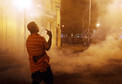 A protester reacts as clouds of smoke and crowd control agents rise shortly after the deadline for a city-wide curfew passed in Baltimore,