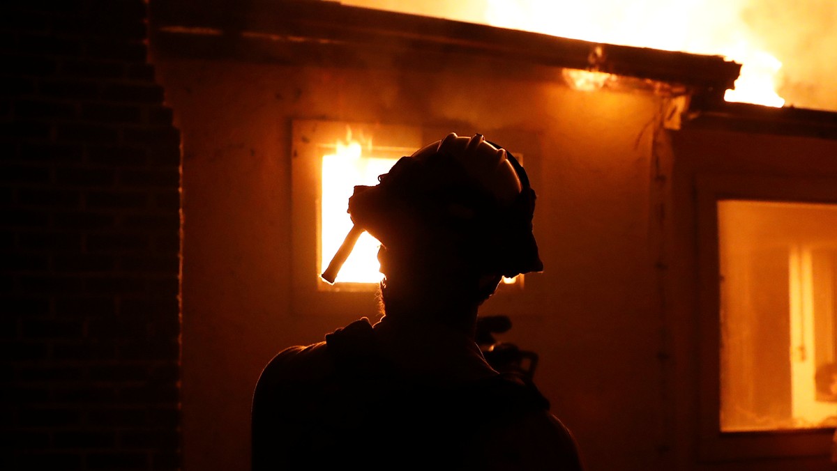 A firefighter monitors a burning structure while battling the Clayton Fire at Lower Lake in California