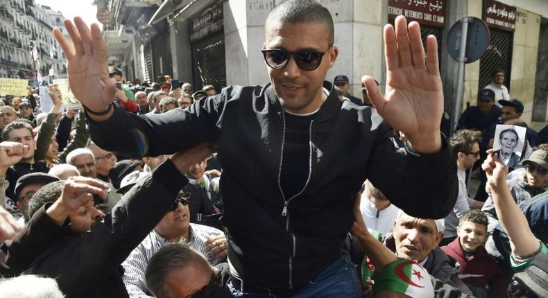 Algerian protesters carry journalist Khaled Drareni, who was arrested while covering an anti-government protest and was accused of inciting an unarmed gathering and damaging national integrity, on their shoulders on March 6, 2020 in Algiers