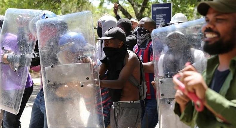 Students demanding free education use shields belonging to private security during clashes with police officers at the Johannesburg's University of the Witwatersrand