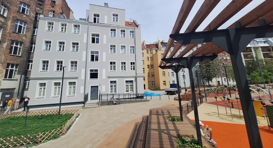 Elewacja, która wcześniej nie miała nawet tynku, zyskała nowe oblicze - jasną kolorystykę i zielone akcenty. Całość dopełniają eleganckie, białe naczółki okienne, które podkreślają charakter obiektu. 