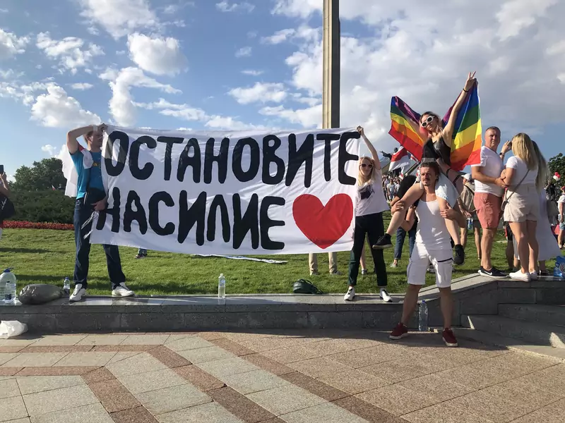 Andrei Zavalei na proteście w Mińsku z tęczową flagą Na plakacie napis &quot;Zatrzymać przemoc&quot;