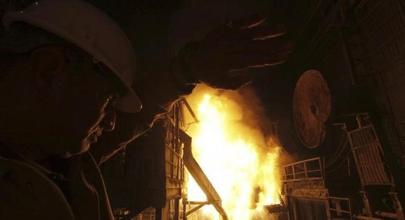 An engineer covers his face as workers pour molten iron into a container at a factory belonging to Ezz Steel, Egypt's largest steel producer, at an industrial complex in Sadat City, 94 km (58 miles) north of Cairo, April 17, 2013. REUTERS/Amr Abdallah Dalsh