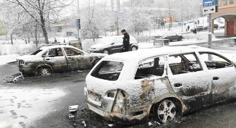 A policeman investigates a burned out car in the suburb Rinkeby, outside Stockholm, on February 21, 2017