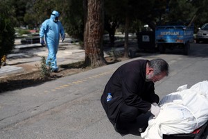 A relative reacts before the burial of the journalist Abdollah Zavieh, who passed away due to coronavirus disease (COVID-19), at Behesht Zahra cemetery in Tehran