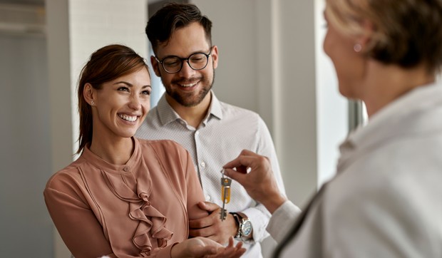 stock-photo-happy-couple-buying-their-new-home-and-receiving-keys-from-real-estate-agent-1753744661